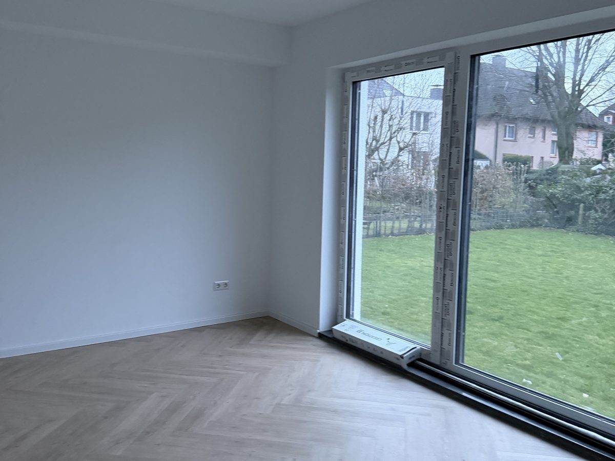 Innenraum der sanierten Stadtvilla in Bochum mit Fischgrätparkett und bodentiefer Fensterfront zum Garten